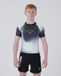 Kingz Galaxy Youth Rashguard Black White - Full Body Front View Teen Boy Athlete Short Sleeve Black White Ombre Galaxy Pattern Gold Star KINGZ Gold Text Crown Logo Black Shorts Kids BJJ [color:Black/Galaxy]