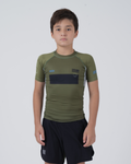 Kingz Trooper Youth Rashguard Military Green - Full Body Front View Young Boy Athlete Short Sleeve Olive Green Black Chest Band Flag Patches Gray Side Panels Black Shorts Kids BJJ [color:Military Green]