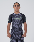Kingz Viper Youth Rashguard Black Purple - Full Body Front View Teen Boy Athlete Short Sleeve Hexagonal Viper Scale Pattern KINGZ Text Green Crown Logo Purple Collar Matching Shorts Kids [color:Black/Purple Patterned]