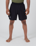 Kingz Trooper Hybrid Shorts Black Olive - Full Body Front View Male Athlete Solid Black Outer Shell Olive Green Inner Compression Shorts Visible Blue KINGZ Badge Right Thigh Circular Crown Badge Flag Badge Left Leg Tactical Military Aesthetic Men's Grappling Shorts [color:Black/Green]