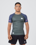 Kingz Draft Rashguard Storm Blue - Full Body Front View Male Athlete Short Sleeve Gray Charcoal Body Blue Raglan Sleeves White Crown Logo Pink KINGZ Labels Crown Badge Black Shorts [color:Storm Blue]
