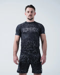 Kingz Acid Wash Rashguard Black - Full Body Front View Male Athlete Short Sleeve Black White Dot Acid Wash Pattern Large KINGZ Text Chest Matching Shorts Modern Design [color:Black/Acid]